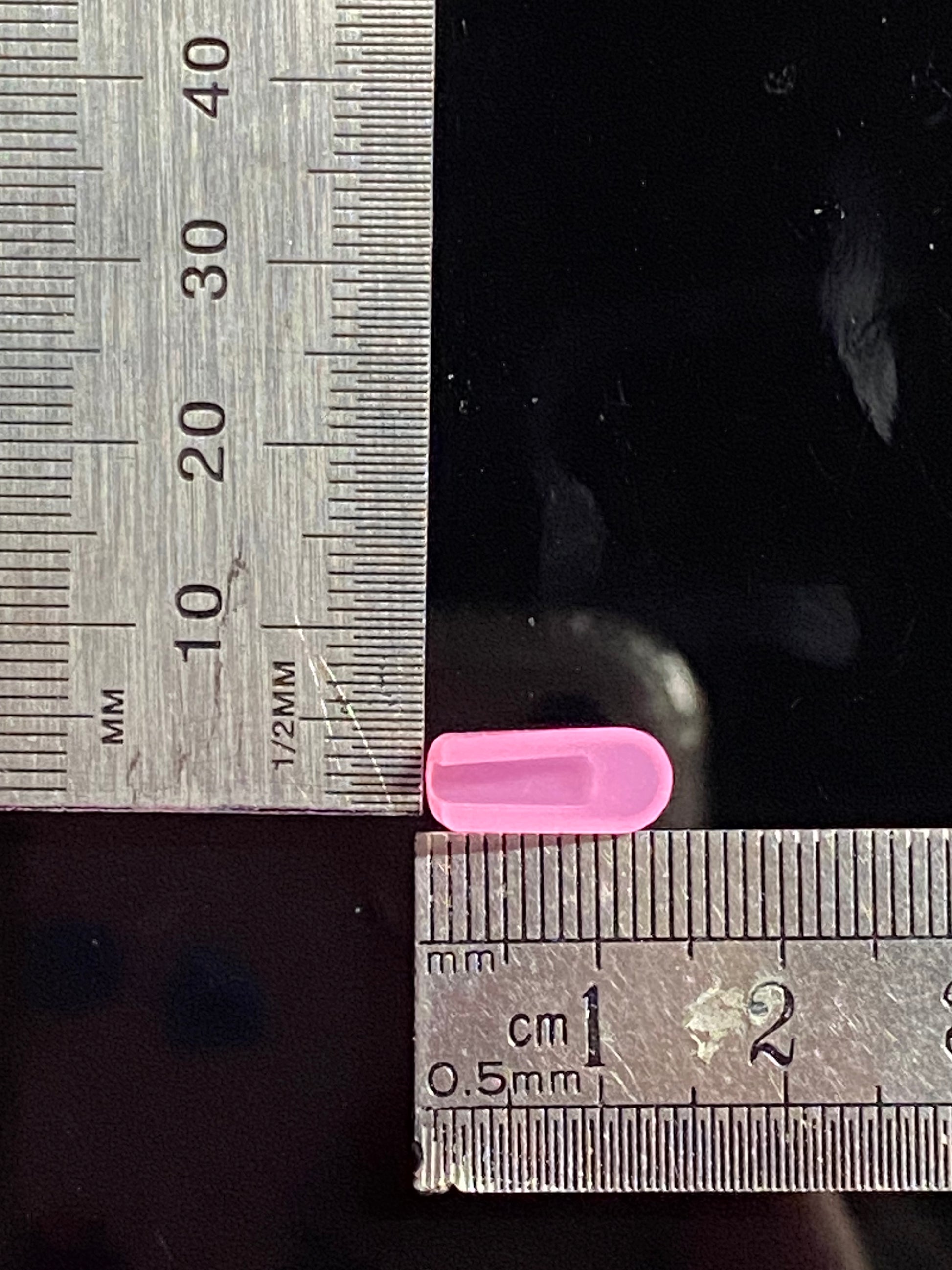 Hot pink end cap, inverse view against ruler. Measuring both base and length