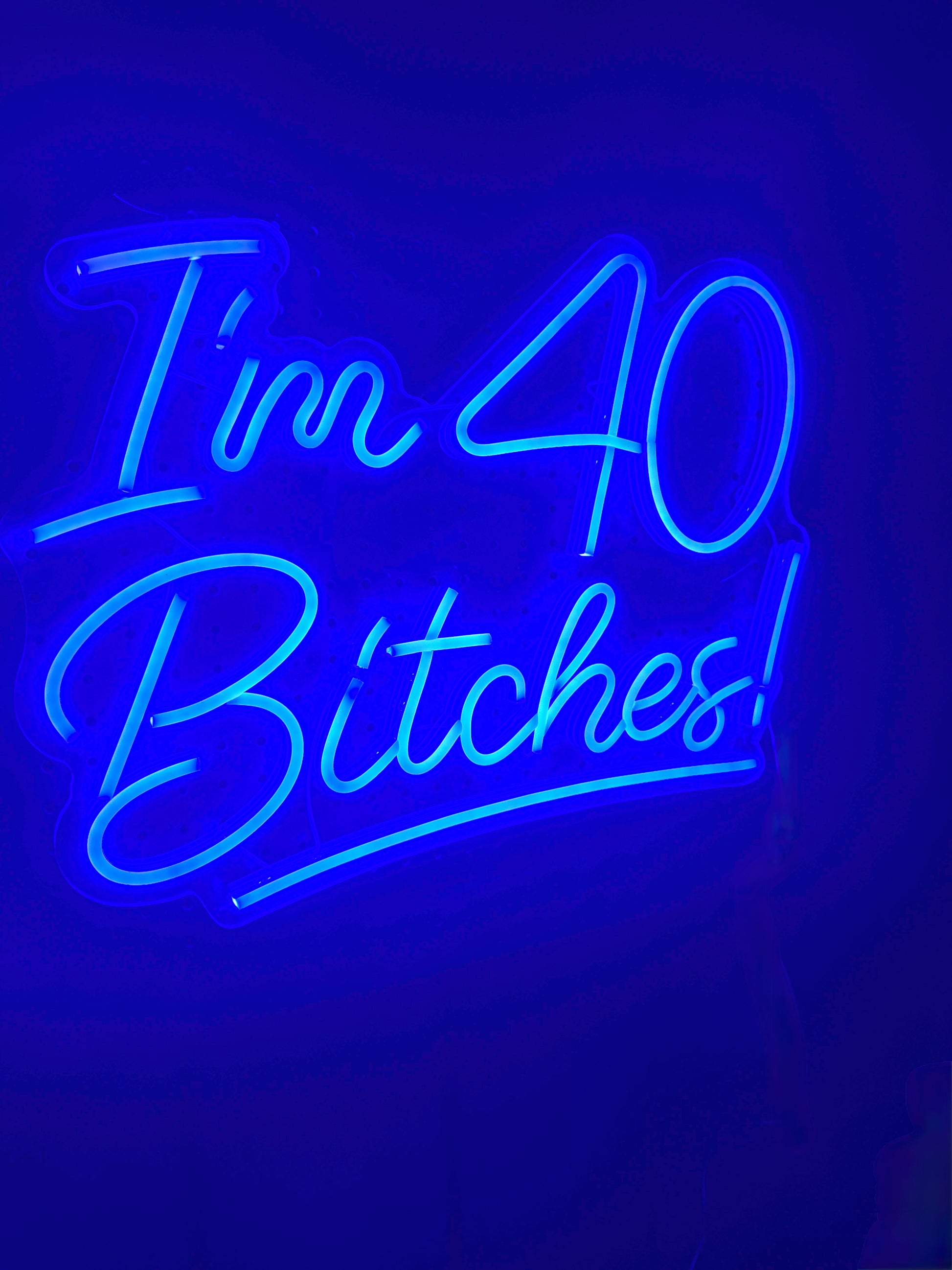 Neon sign with blue text 'I'm 40 Bitches!' 