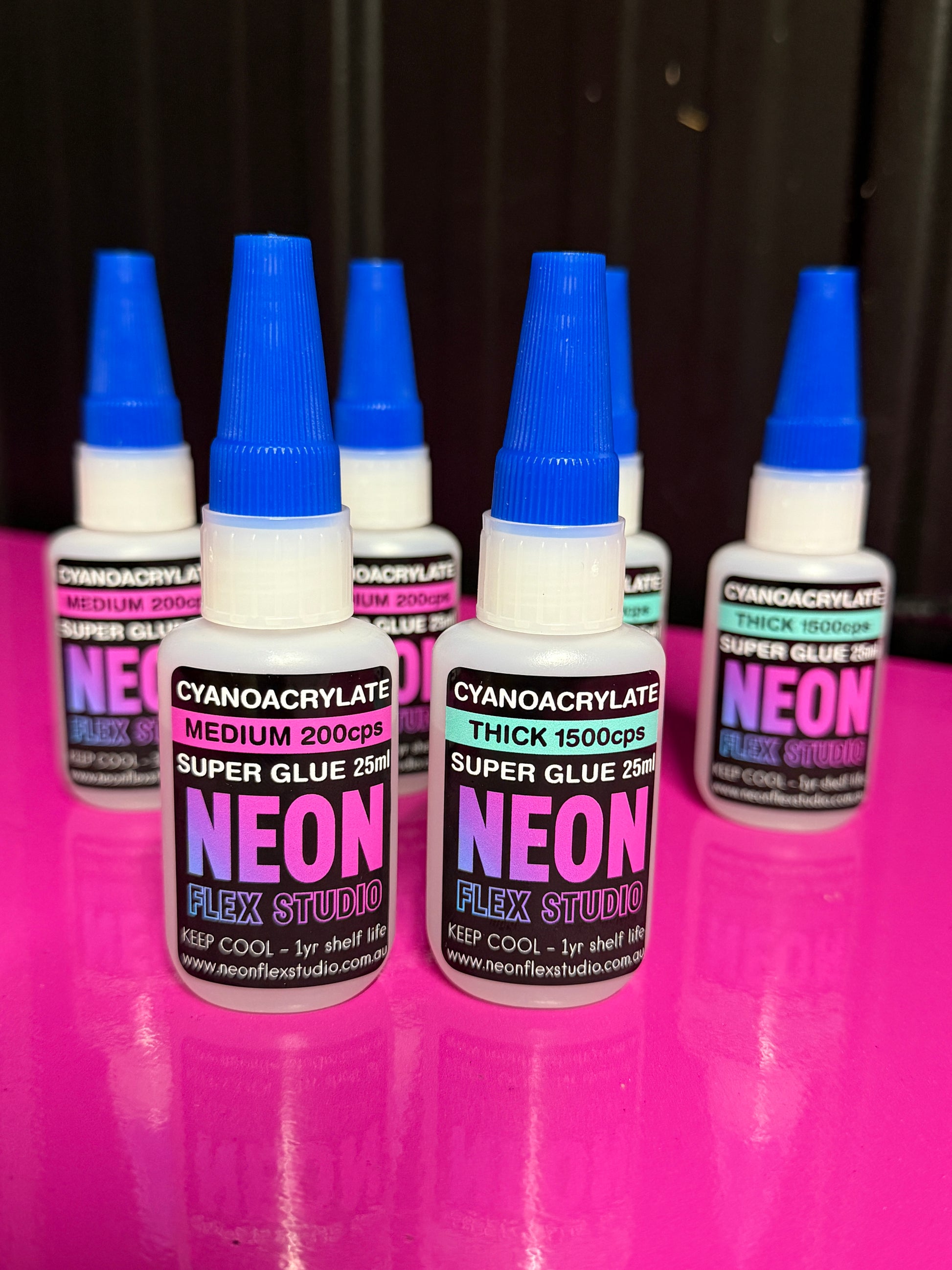 Neon Flex Studio glue bottles on a pink and black background